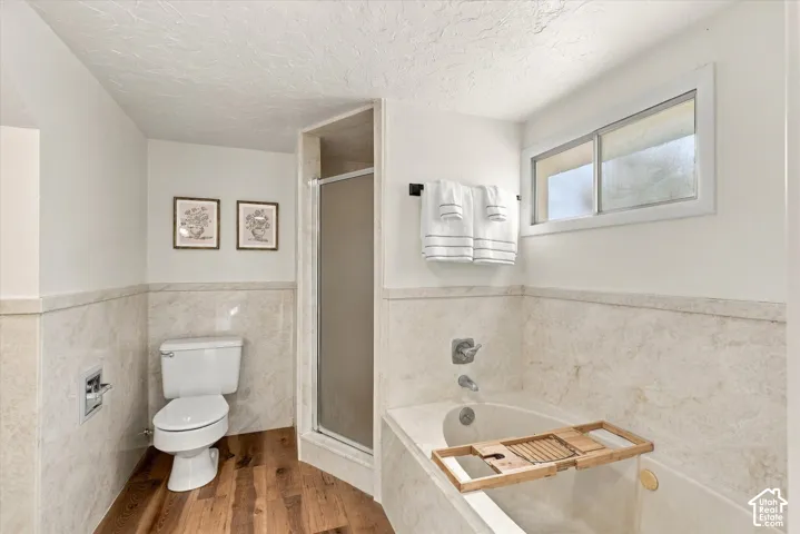 Full-height wall surround, wood-finish flooring, built-in soaking tub, separate shower enclosure, and sliding horizontal window