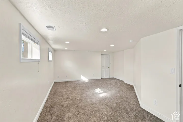 Neutral-toned interior space featuring wall-to-wall carpeting, recessed ceiling lighting, and multiple slider windows