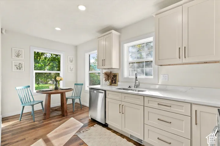 Kitchen featuring shaker-style cabinetry, stone countertops, stainless steel undermount sink with gooseneck faucet, stainless steel dishwasher, and wood-finish flooring