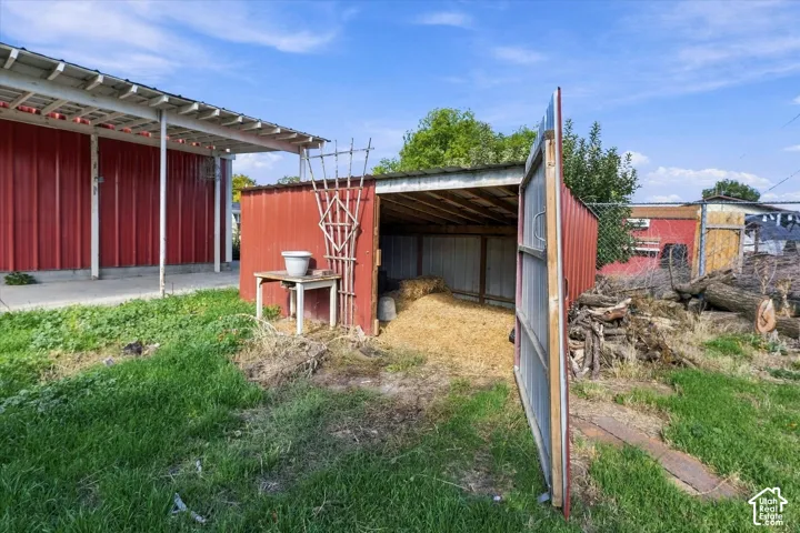Outbuilding featuring red metal siding, a single-slope roof, and an open storage stall