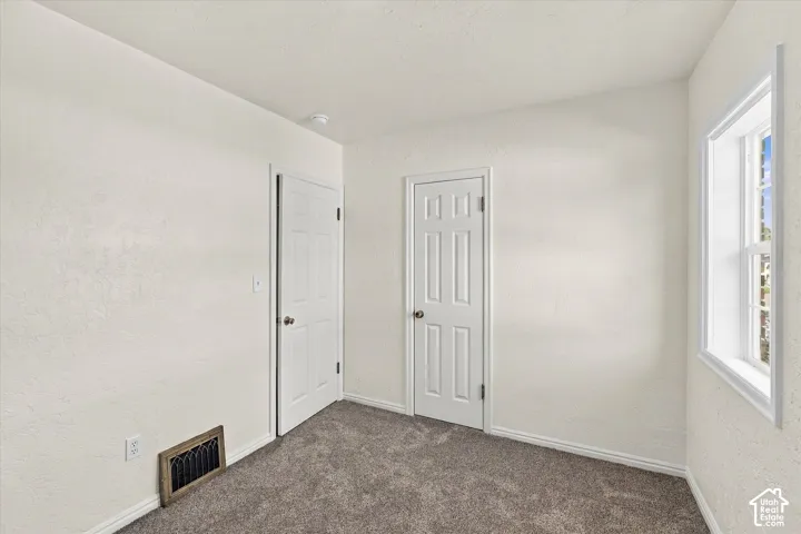 Neutral-toned walls, wall-to-wall carpeting, and a double-hung window with white trim