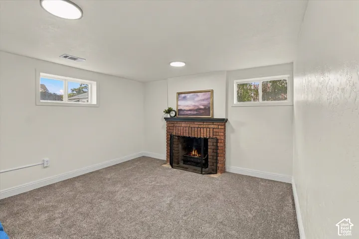 Interior space featuring a brick fireplace with a mantel, neutral wall-to-wall carpeting, recessed ceiling lighting, and dual windows