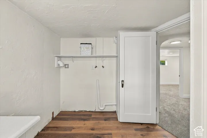 Utility area featuring wood-finish flooring, a white wall-mounted shelf, and dedicated washer and dryer