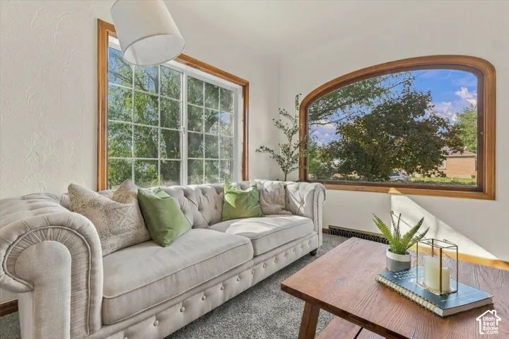 Room featuring a large grid-pattern window and an arched window, both framed in natural wood trim, complemented by a suspended light fixture
