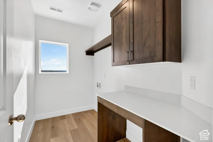 Laundry area featuring dark wood-finish cabinetry, a crisp white countertop, a matching built-in shelf, and wood-finish flooring