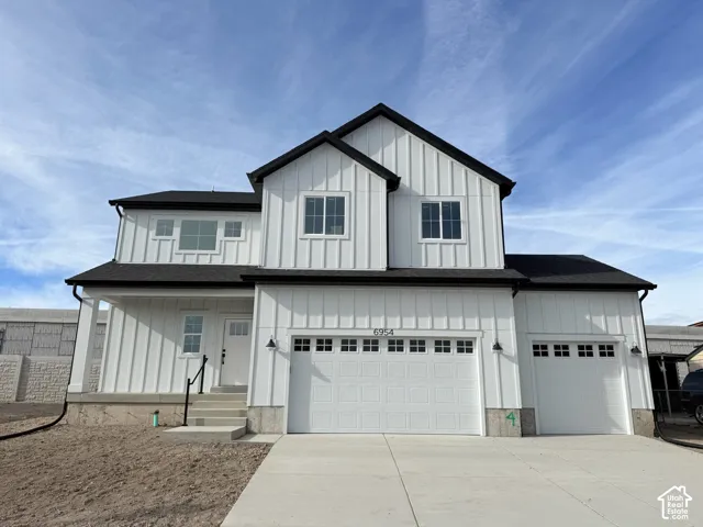 Two-story exterior featuring white vertical siding, dark roof shingles, an attached three-car garage, and concrete driveway