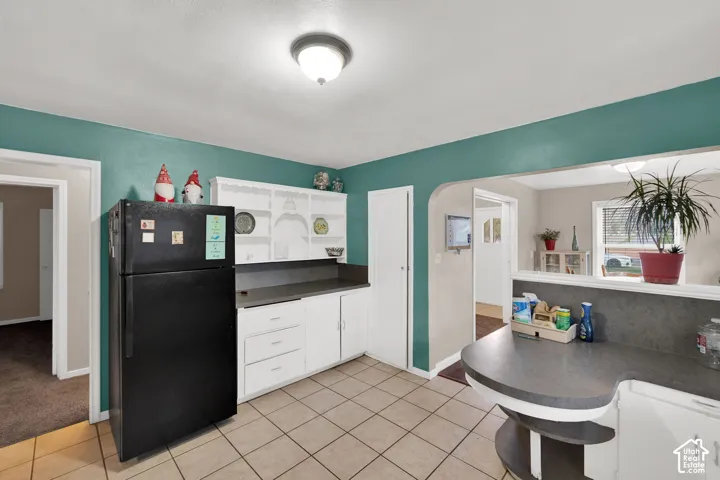 Kitchen featuring white built-in cabinetry, arched entryway, and tile flooring