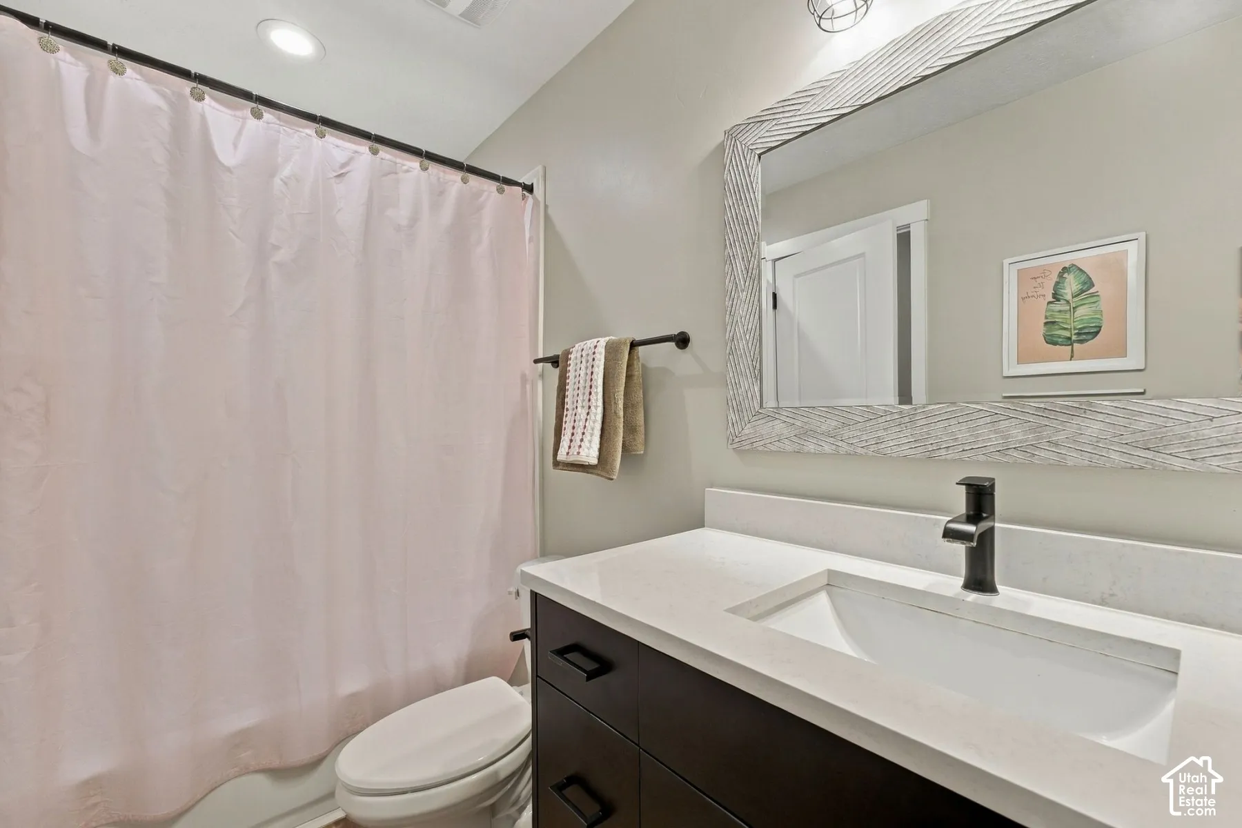 Bathroom vanity featuring a stone countertop, integrated basin, matte black faucet, and dark-finish cabinetry with linear hardware