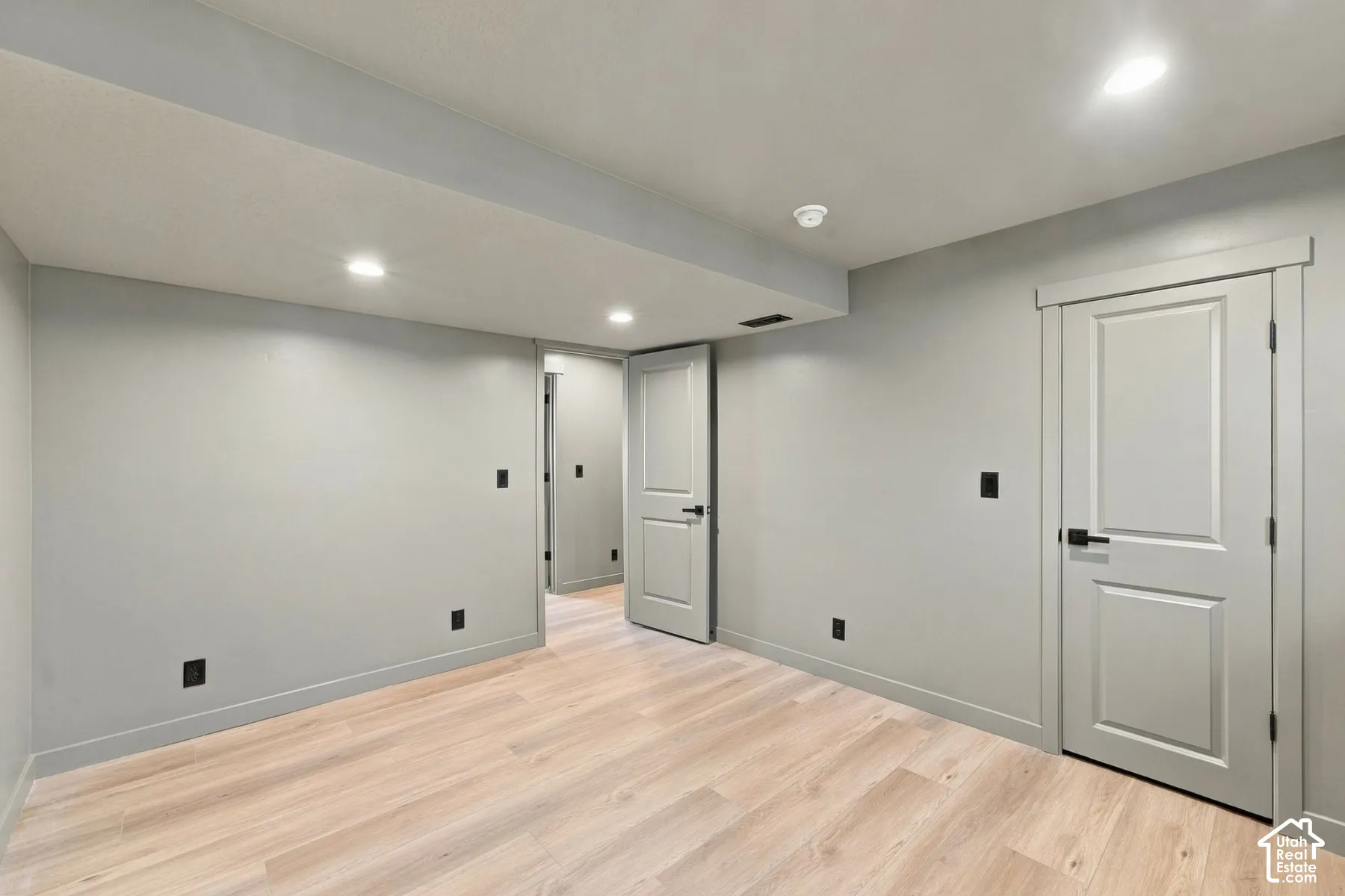 Interior space featuring light-toned wood-finish flooring, neutral wall paint, recessed lighting, and doors with matte black hardware