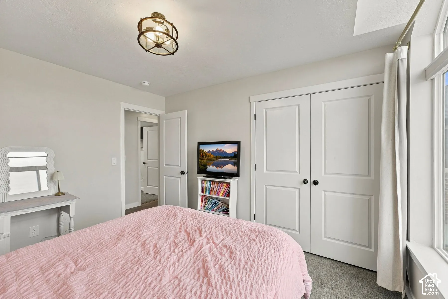 Neutral-toned room featuring a multi-light drum flush-mount fixture, two-panel interior doors, double-door closet, and large pane window
