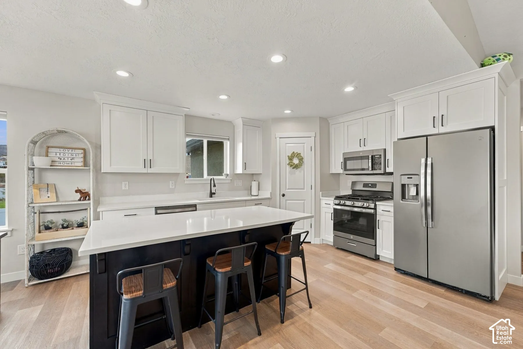 Kitchen featuring white cabinetry, center island with a stone-finish countertop, stainless steel appliances, recessed lighting, and wood-finish flooring