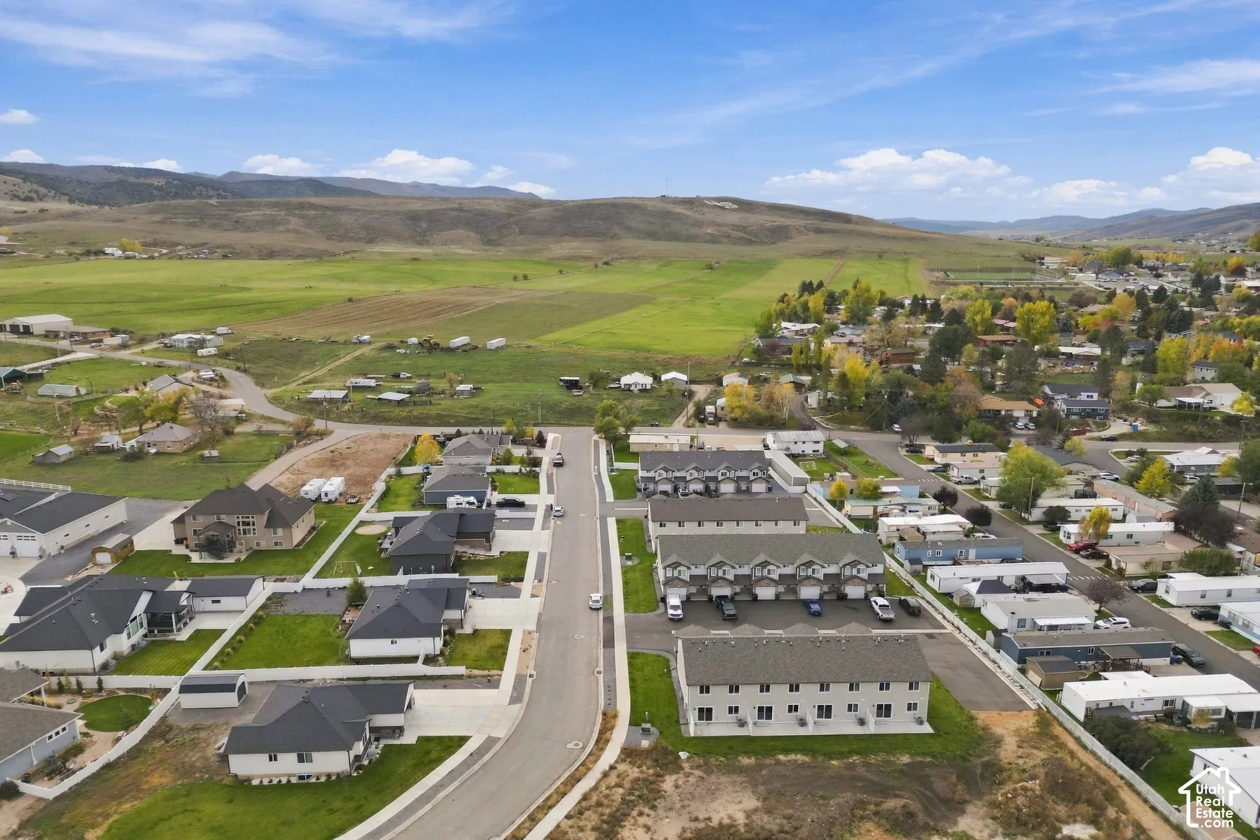 Aerial perspective of a multi-unit residential development featuring attached garage structures, asphalt driveways, and expansive mountain scenery