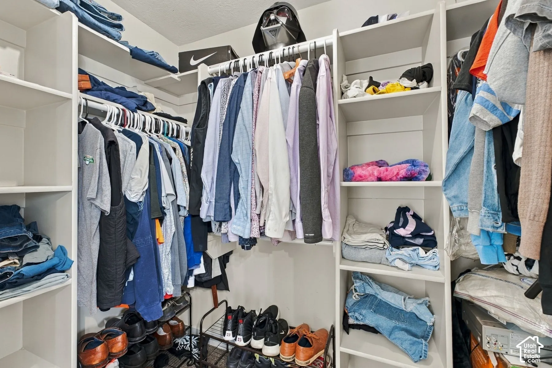 Walk-in closet featuring white built-in shelving units, adjustable open-tier storage, and integrated hanging rods