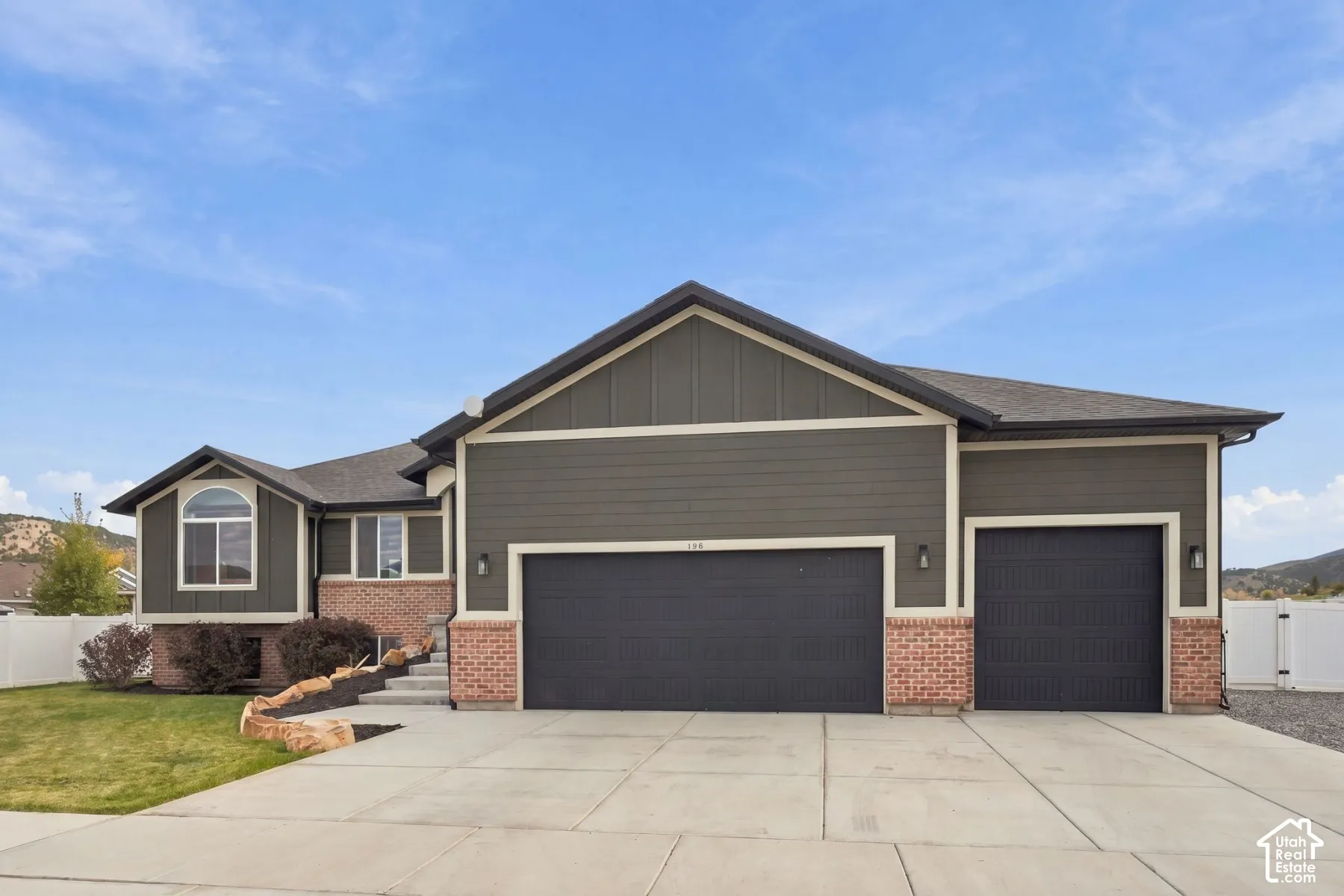 Multi-level exterior featuring a combination of horizontal siding, brick masonry, a three-car garage, and concrete driveway