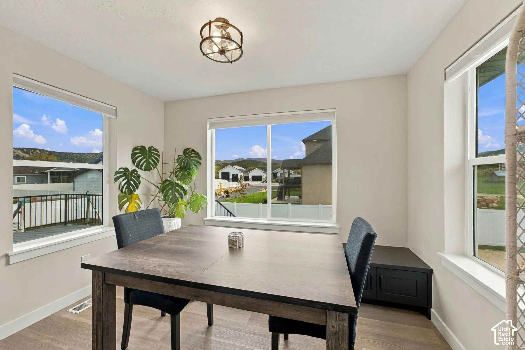Bright room featuring wood-finish flooring, three large windows, and a flush-mount geometric ceiling light fixture