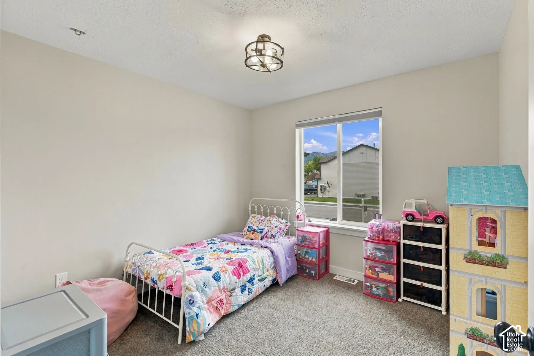 Neutral-toned walls, neutral carpeting, large window with natural lighting, and geometric flush-mount ceiling light fixture