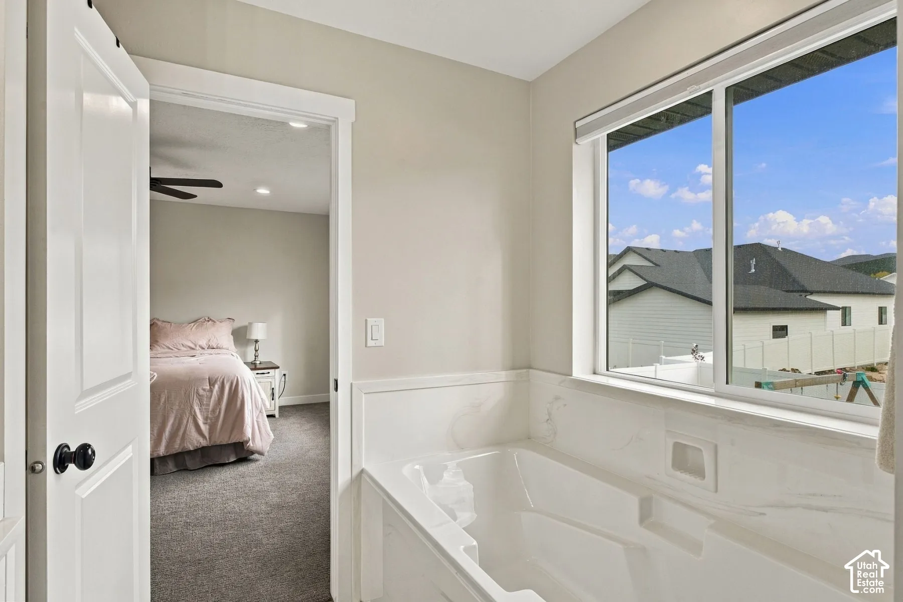 Soaking tub featuring a stone-surround deck, recessed niche, and sliding window