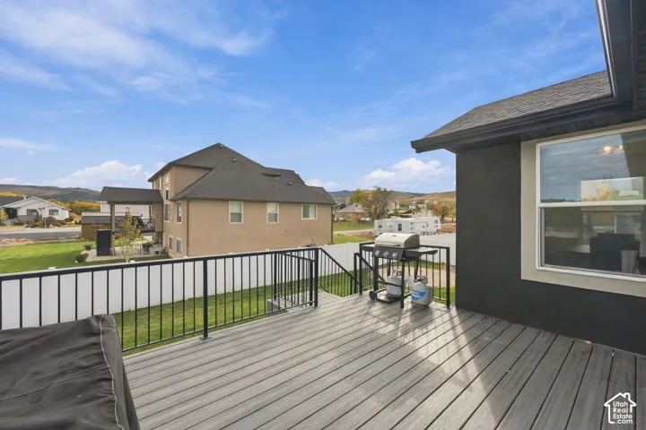 Elevated composite decking featuring black metal railing, stairs to the backyard, and white vinyl privacy fencing