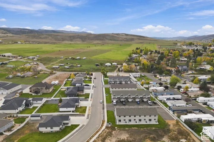 Aerial perspective of a multi-unit residential development featuring attached garage structures, asphalt driveways, and expansive mountain scenery