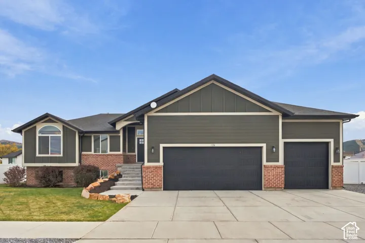 Exterior facade featuring horizontal siding, brick veneer accents, a multi-car garage, and concrete driveway