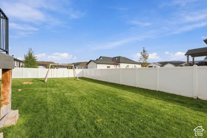 Expansive backyard featuring a level lawn, white vinyl privacy fencing, and an elevated wood deck