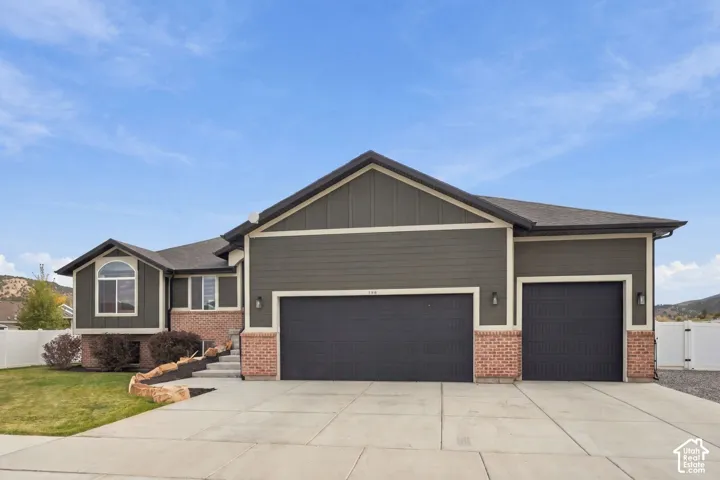 Multi-level exterior featuring a combination of horizontal siding, brick masonry, a three-car garage, and concrete driveway