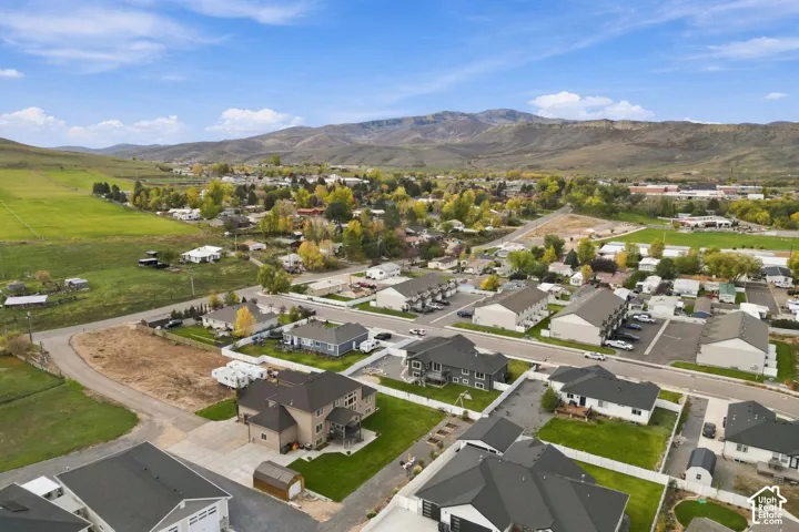 Aerial perspective of a residential neighborhood featuring mountain topography, sprawling green acreage, and multi-unit housing