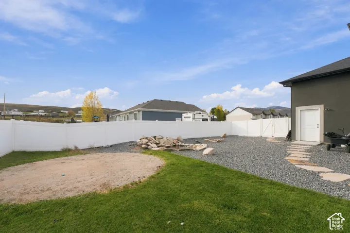 Fully enclosed backyard featuring white vinyl privacy fencing, stone hardscaping, decorative rock garden, and a stone paver walkway