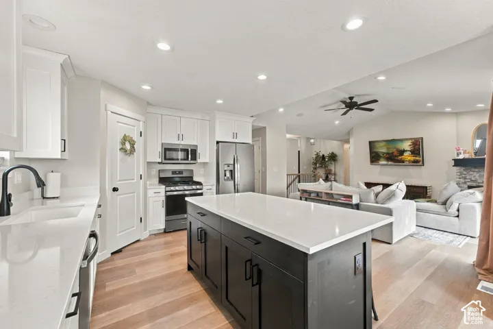 Kitchen featuring white shaker-style cabinetry, dark contrast kitchen island with a light-toned countertop, wood-finish flooring, and recessed ceiling lighting