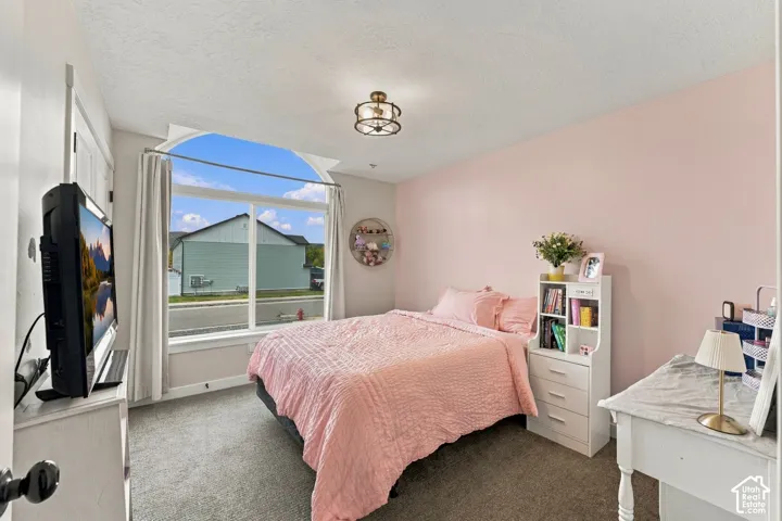 Room featuring an arched window, neutral wall paint, wall-to-wall carpeting, and a semi-flush mount cage-style light fixture