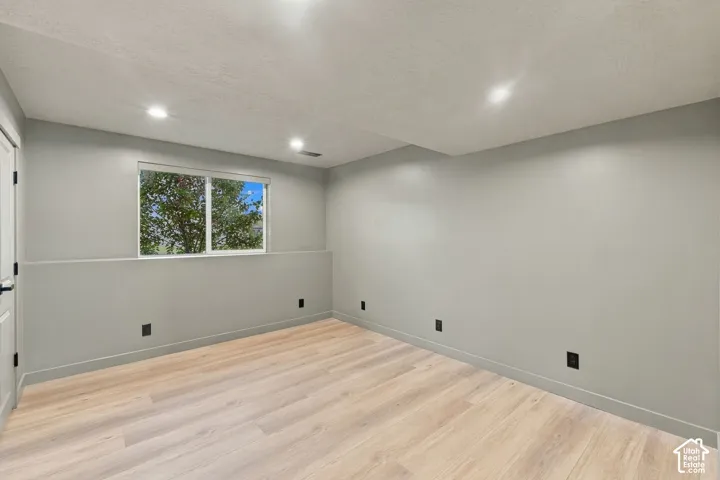 Neutral-toned room featuring light wood-finish flooring, recessed lighting, and a single-pane horizontal window