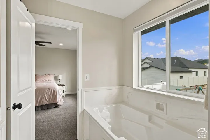 Soaking tub featuring a stone-surround deck, recessed niche, and sliding window