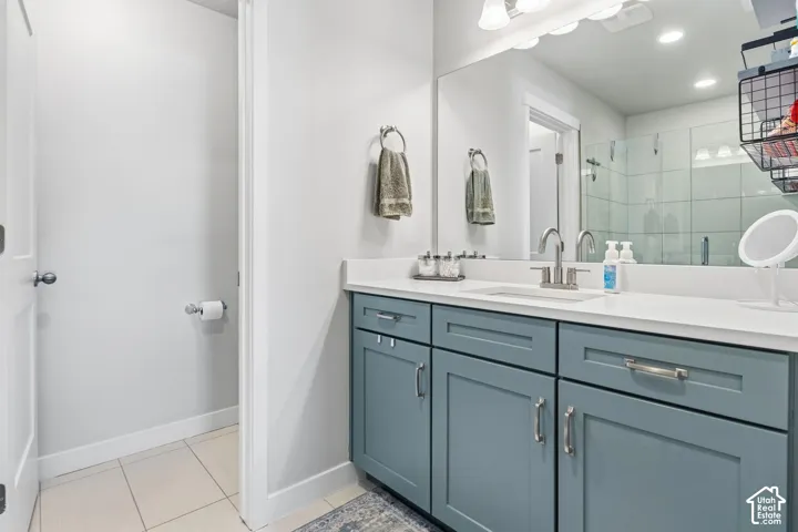 Shaker-style cabinetry with blue matte finish, solid-surface countertop, rectangular undermount sink, polished chrome faucet, and expansive wall-mounted mirror