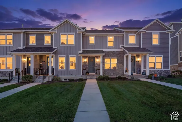 Multi-unit residential exterior featuring vertical siding, stone veneer accents, covered entryways with columns, and concrete walkways