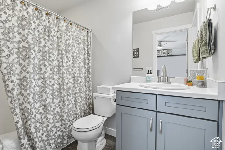 Bathroom featuring a grey/blue shaker-style vanity cabinet, white solid-surface countertop with an integrated basin, polished chrome faucet, full-width mirror, and shower-tub combination