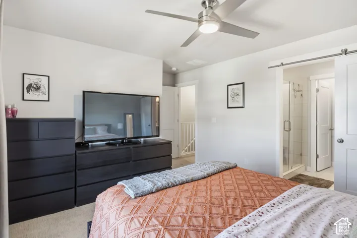 Main bedroom featuring a ceiling fan, sliding barn door, and access to bathroom
