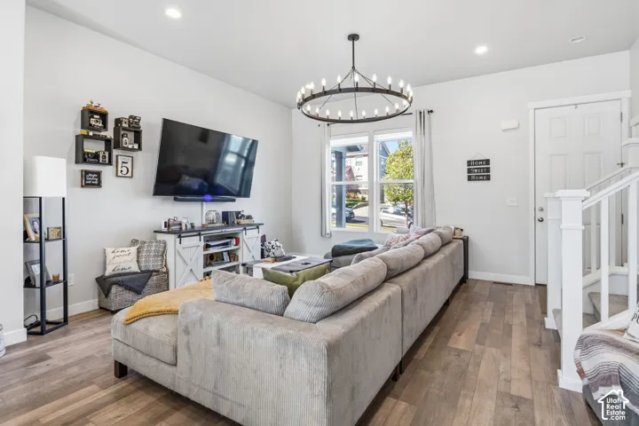 Open-concept area featuring wood-finish flooring, a contemporary circular chandelier, recessed lighting, and a white staircase with a wooden handrail