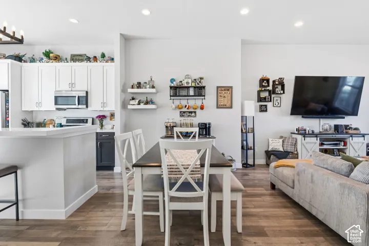 Open-concept kitchen featuring white cabinetry, stainless steel microwave,  island, and wood-finish flooring