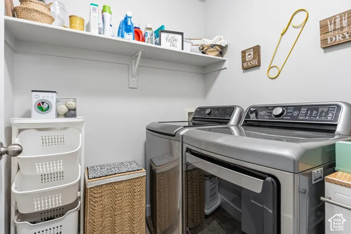 Laundry area featuring a full-width wall-mounted storage shelf and stainless steel appliances