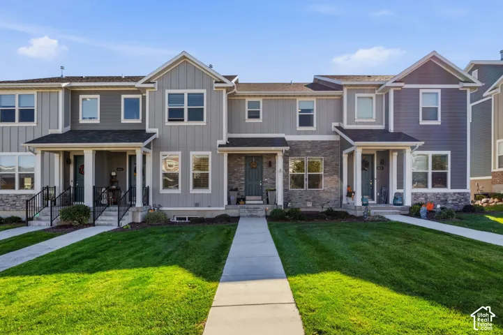 Multi-unit exterior featuring vertical siding, stone veneer accents, covered entryway porches with support columns, and dual-pane windows