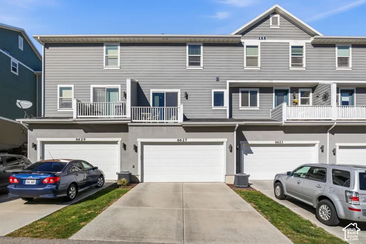 South side of home. Multi-level townhouse exterior featuring gray horizontal siding, stucco lower facade, attached two-car garages, and elevated balconies with white railings