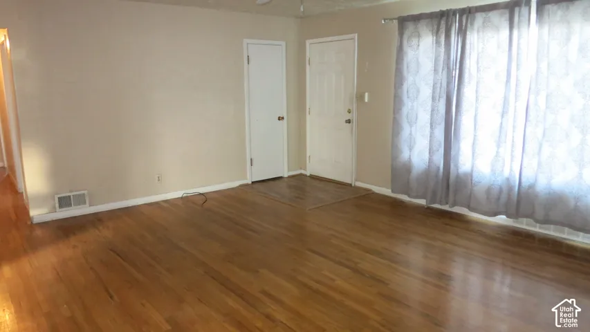 Living area featuring polished wood-finish flooring, neutral wall paint, and a multi-panel exterior entry door