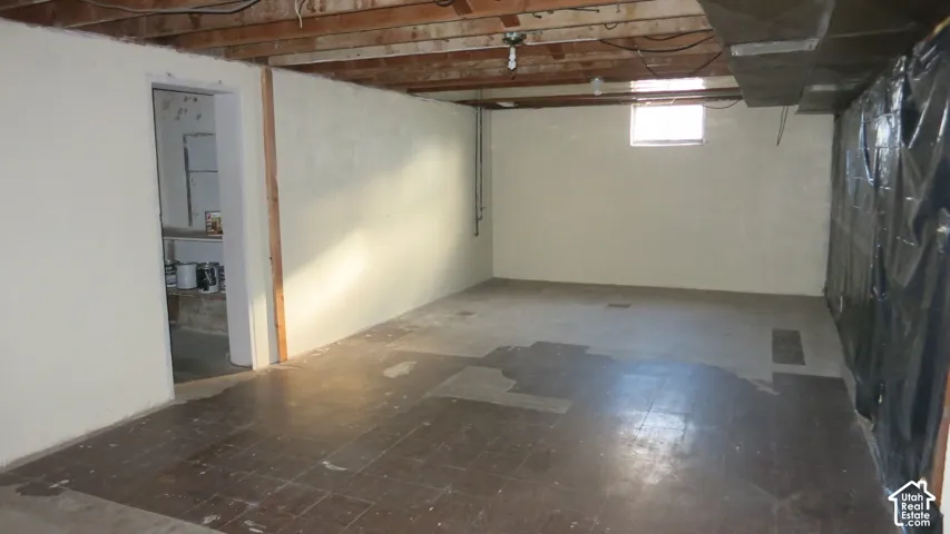 Unfinished interior space featuring exposed wood ceiling joists, neutral-toned walls, and a single window