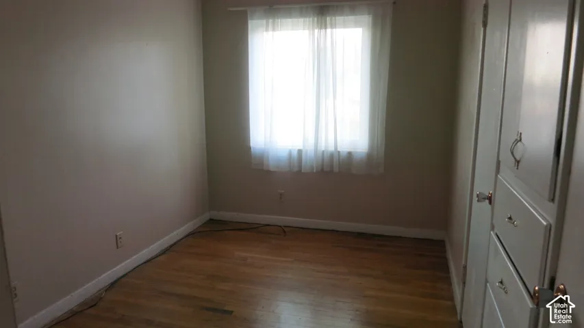 Wood-finish flooring, neutral wall tones, sliding window with natural light, and built-in closet cabinetry