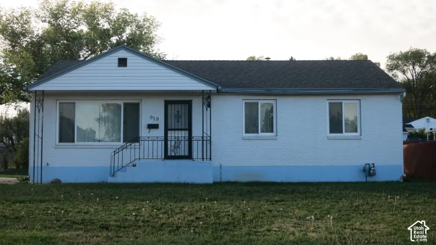 Single-story residence featuring a painted brick exterior, gabled roofline, horizontal siding on the front gable, and a metal-railed porch entry