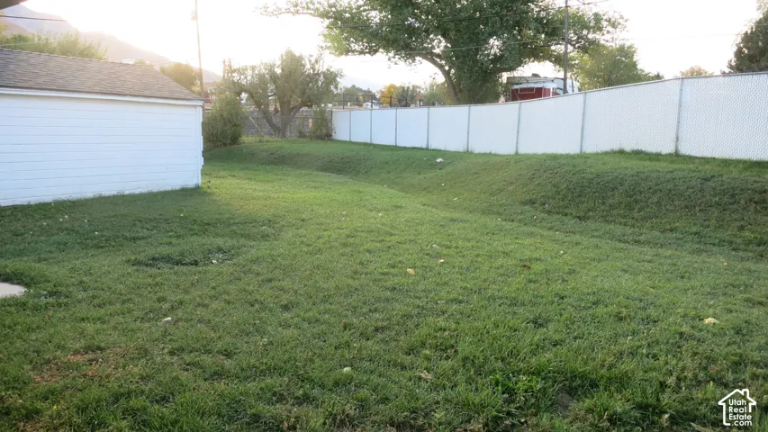 Backyard featuring a grass lawn, white horizontal siding exterior, and white privacy fencing