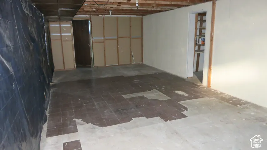 Unfinished lower level featuring concrete flooring, exposed ceiling joists, and integrated storage shelving