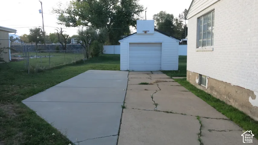 Detached single-car garage with white siding, concrete driveway, and white masonry exterior walls
