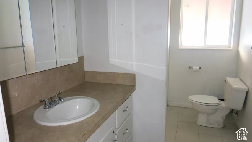 Bathroom featuring a vanity with a solid-surface countertop, an integrated oval sink, dual-mirrored medicine cabinet, and tile flooring