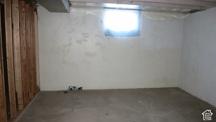 Unfinished interior space featuring exposed wood-stud framing, concrete flooring, and a window